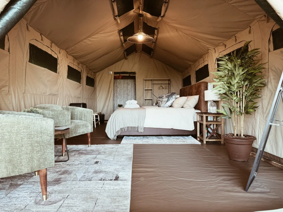 Spacious luxury safari tent with a neatly presented bed and lounge seating