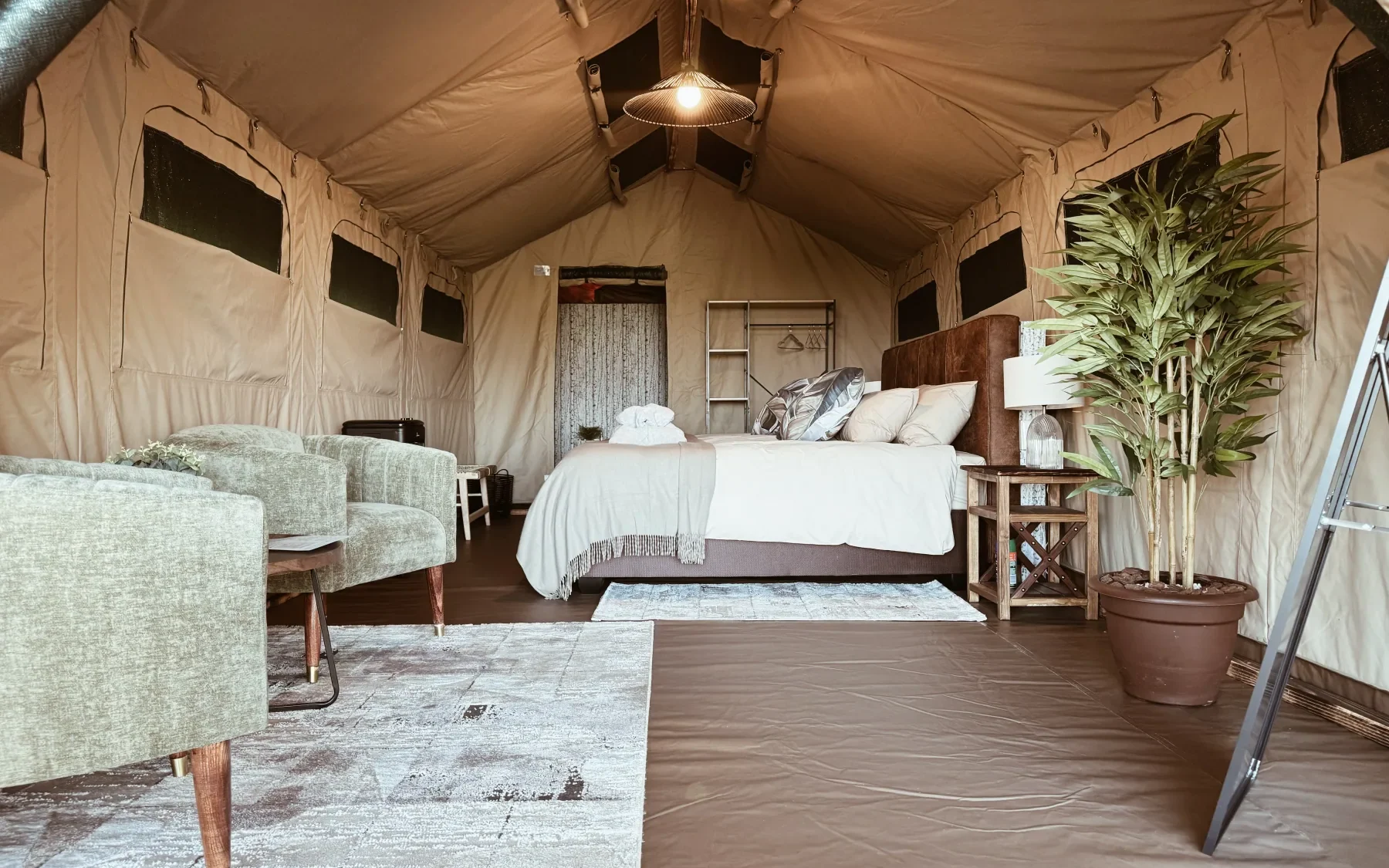 Spacious luxury safari tent with a neatly presented bed and lounge seating